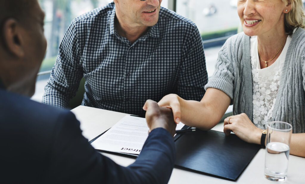 A man shaking hands with another man over papers.